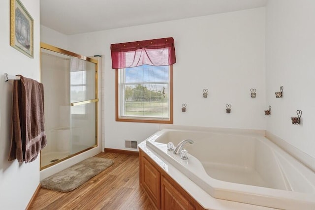 3025 Shawnee Rd, Bridgman, MI 49106 - bathroom with wood finished floors, a garden tub, a stall shower, and baseboards