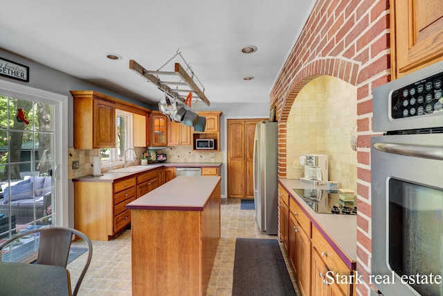 300 N 2nd Ave, Fruitport, MI 49415 - kitchen featuring stainless steel appliances, a sink, a kitchen island, backsplash, and light countertops