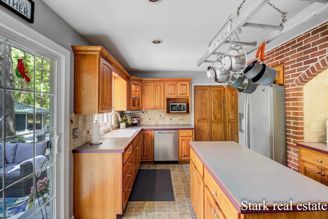 300 N 2nd Ave, Fruitport, MI 49415 - kitchen featuring appliances with stainless steel finishes, a sink, tasteful backsplash, light countertops, and brick wall