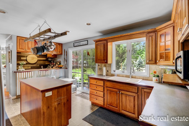 300 N 2nd Ave, Fruitport, MI 49415 - kitchen with a sink, stainless steel microwave, decorative backsplash, brown cabinets, and a center island