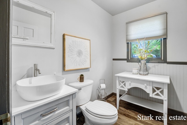 300 N 2nd Ave, Fruitport, MI 49415 - bathroom featuring vanity, wood finished floors, toilet, and a wainscoted wall