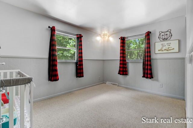 300 N 2nd Ave, Fruitport, MI 49415 - unfurnished bedroom featuring multiple windows, carpet flooring, and a crib