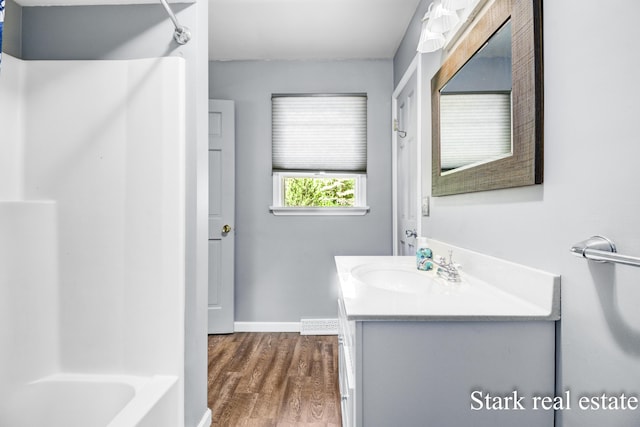 300 N 2nd Ave, Fruitport, MI 49415 - full bathroom with vanity, wood finished floors, baseboards, and bathtub / shower combination