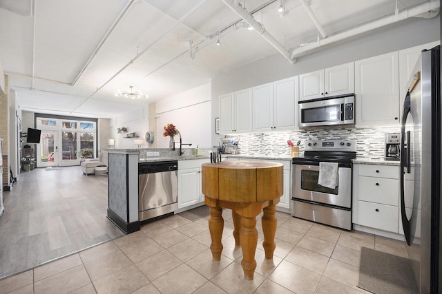 600 Broadway Ave NW Unit 117, Grand Rapids, MI 49504 - kitchen with stainless steel appliances, white cabinetry, decorative backsplash, light stone counters, and a chandelier