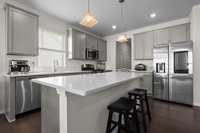 2771 Silo Dr, Saline, MI 48176 - kitchen with appliances with stainless steel finishes, gray cabinets, a sink, a kitchen island, and tasteful backsplash