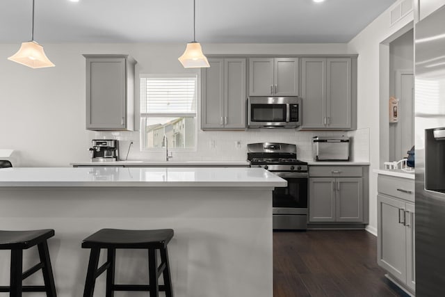 2771 Silo Dr, Saline, MI 48176 - kitchen with gray cabinetry, appliances with stainless steel finishes, backsplash, and dark wood-style floors
