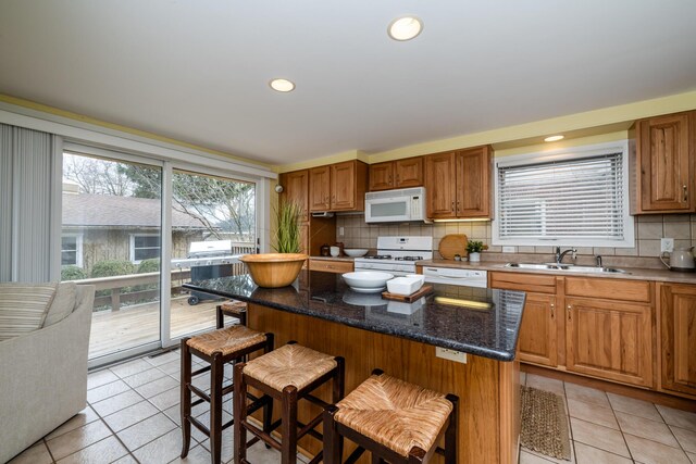 1701 Forres Ave, Saint Joseph, MI 49085 - kitchen featuring white appliances, a sink, backsplash, a breakfast bar area, and light tile patterned floors
