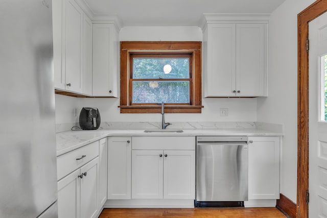 710 S 1st St, Ann Arbor, MI 48103 - kitchen featuring stainless steel dishwasher, freestanding refrigerator, a sink, white cabinetry, and light stone countertops