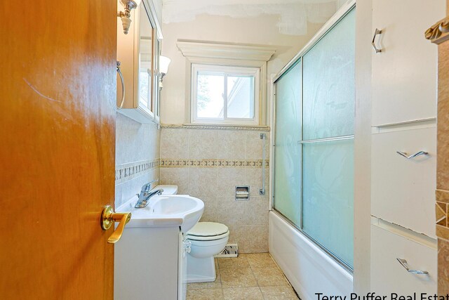 2576 Vine Ave, Muskegon, MI 49442 - full bathroom with vanity, tile walls, toilet, tile patterned flooring, and combined bath / shower with glass door