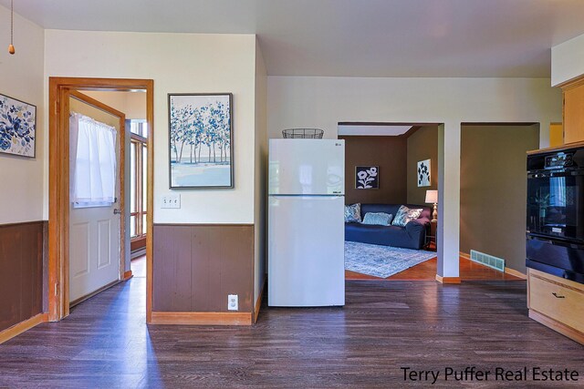 2576 Vine Ave, Muskegon, MI 49442 - kitchen featuring freestanding refrigerator, wood finished floors, a warming drawer, black oven, and a wainscoted wall