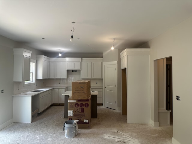 8827 Loggers Spur SE, Caledonia, MI 49316 - kitchen featuring a kitchen island, a sink, decorative backsplash, and baseboards