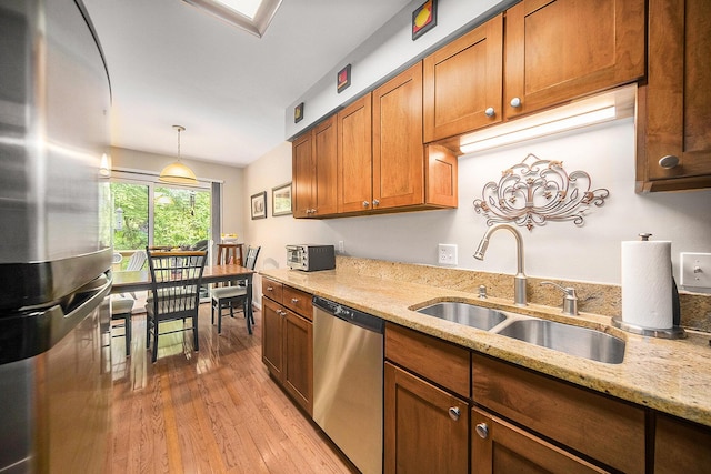 7643 Cottonwood Ln, Dexter, MI 48130 - kitchen with appliances with stainless steel finishes, a sink, light wood-style flooring, light stone countertops, and brown cabinets