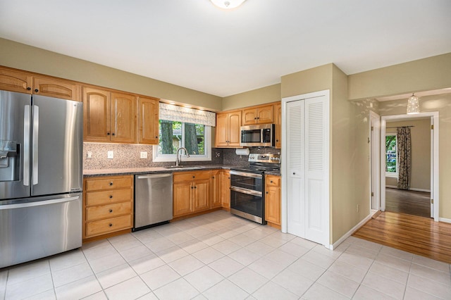 1231 Naples Ct, Ann Arbor, MI 48103 - kitchen with stainless steel appliances, a sink, backsplash, light tile patterned floors, and baseboards