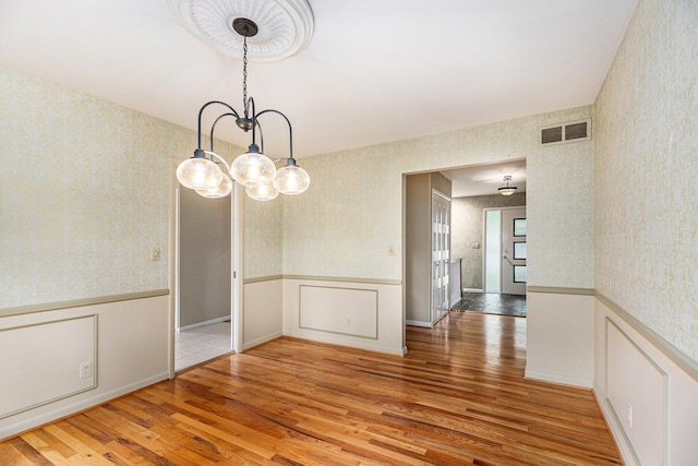 1231 Naples Ct, Ann Arbor, MI 48103 - unfurnished dining area featuring wallpapered walls, a wainscoted wall, wood finished floors, and a chandelier