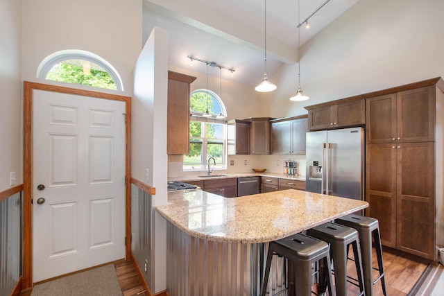 9324 Perry St, Zeeland, MI 49464 - kitchen featuring stainless steel appliances, a sink, a peninsula, light stone countertops, and high vaulted ceiling
