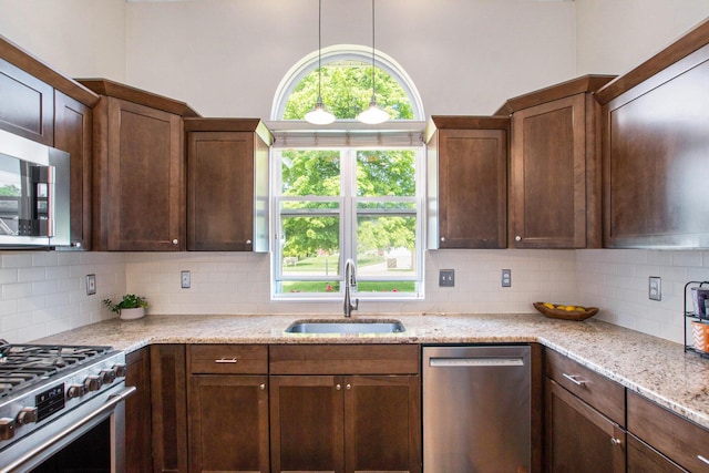 9324 Perry St, Zeeland, MI 49464 - kitchen featuring appliances with stainless steel finishes, a sink, decorative backsplash, light stone counters, and decorative light fixtures