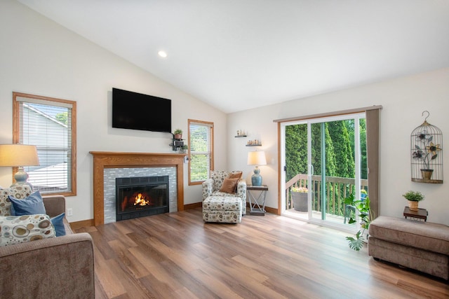 9324 Perry St, Zeeland, MI 49464 - living room featuring healthy amount of natural light, wood finished floors, a tiled fireplace, vaulted ceiling, and recessed lighting