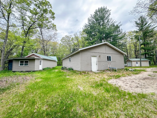 4307 N Mac Rd, Irons, MI 49644 - back of house featuring an outdoor structure, a garage, and view of wooded area