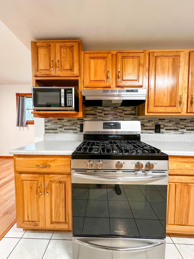 4307 N Mac Rd, Irons, MI 49644 - kitchen with appliances with stainless steel finishes, under cabinet range hood, light countertops, and backsplash