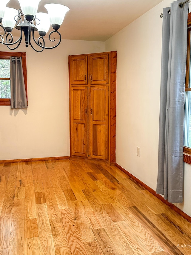 4307 N Mac Rd, Irons, MI 49644 - unfurnished room featuring a chandelier, baseboards, and light wood-style flooring