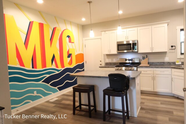 239 Monroe Ave, Muskegon, MI 49441 - kitchen featuring appliances with stainless steel finishes, wood finished floors, a center island, white cabinets, and recessed lighting
