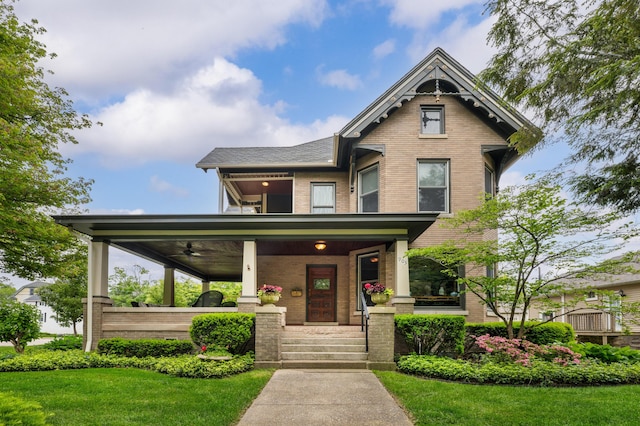 903 Lake Blvd, Saint Joseph, MI 49085 - victorian home featuring brick siding, a porch, ceiling fan, a front yard, and a balcony