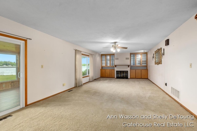 171 Dickerson Vw SW, Stanton, MI 48888 - unfurnished living room with ceiling fan, light colored carpet, baseboards, and a glass covered fireplace