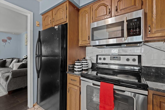 35519 Canyon Dr, Westland, MI 48186 - kitchen with appliances with stainless steel finishes, dark countertops, brown cabinetry, and backsplash