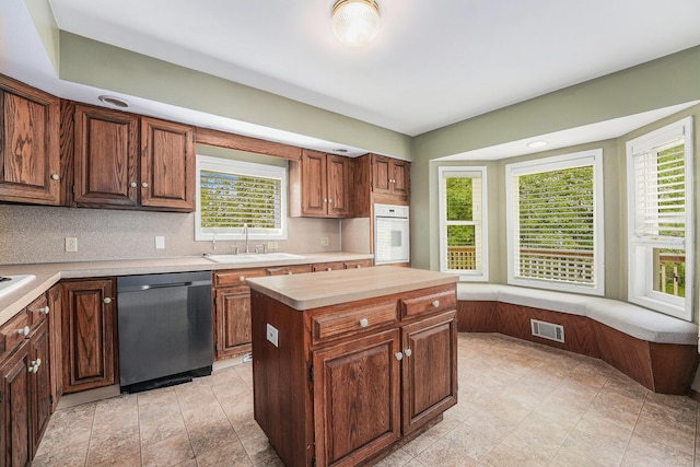 5643 Ivanrest Ave SW, Wyoming, MI 49418 - kitchen with stainless steel dishwasher, a sink, oven, light countertops, and tasteful backsplash