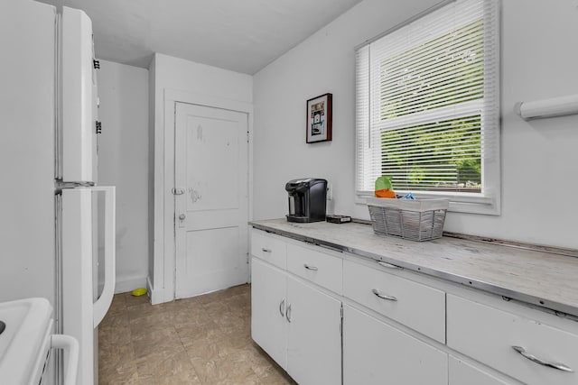 105 Renker Rd, Lansing, MI 48917 - kitchen featuring white cabinetry, freestanding refrigerator, range, and light stone counters