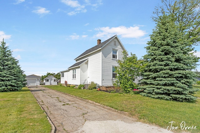 10551 James St, Zeeland, MI 49464 - view of side of property featuring a chimney, a garage, a lawn, and an outdoor structure