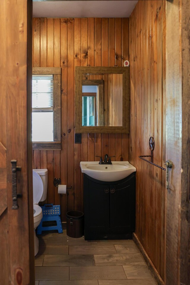 1041 W Arthur Rd, Rothbury, MI 49452 - bathroom with toilet, vanity, wood walls, and wood finished floors