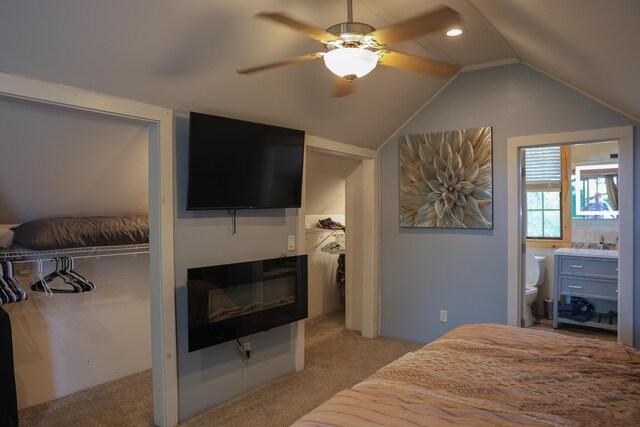1041 W Arthur Rd, Rothbury, MI 49452 - bedroom with light carpet, lofted ceiling, connected bathroom, ceiling fan, and a glass covered fireplace