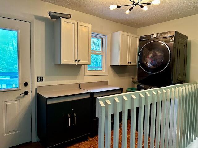 1566 N Fitzgerald Ave, Hesperia, MI 49421 - washroom with cabinet space, a textured ceiling, stacked washer / dryer, and a chandelier