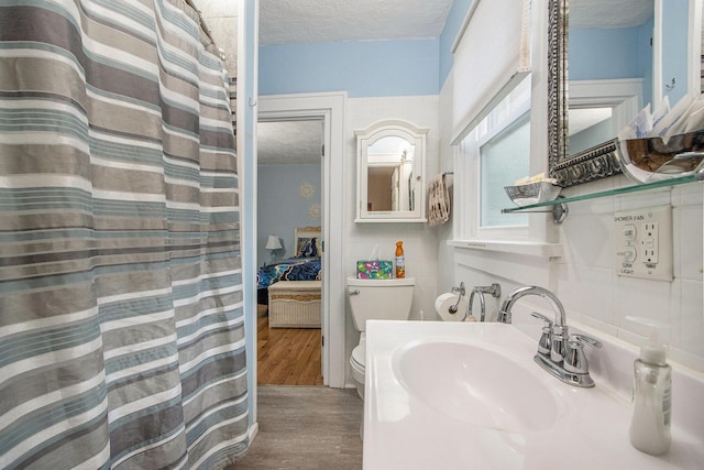 208 Nelson Ave, Kalamazoo, MI 49006 - ensuite bathroom featuring a textured ceiling, a sink, toilet, wood finished floors, and a shower with shower curtain
