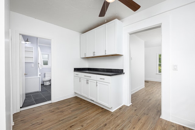 115 Mckinley St, Chelsea, MI 48118 - kitchen with ceiling fan, white cabinets, dark countertops, wood finished floors, and baseboards