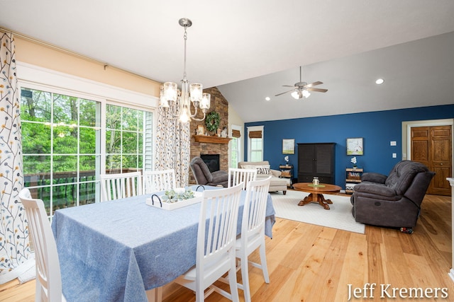7153 Keystone Ct, Jenison, MI 49428 - dining room with light wood-style flooring, vaulted ceiling, a chandelier, a ceiling fan, and a stone fireplace