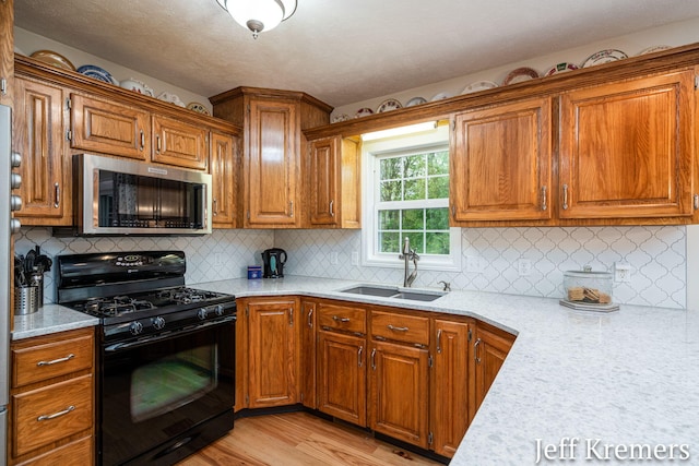 7153 Keystone Ct, Jenison, MI 49428 - kitchen featuring stainless steel microwave, black range with gas stovetop, a sink, light wood-style floors, and brown cabinets