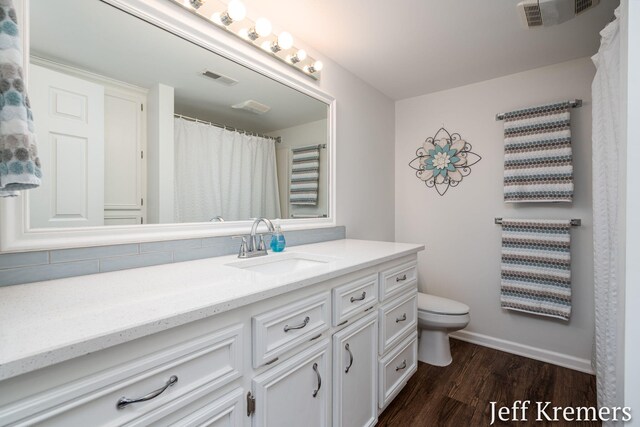 7153 Keystone Ct, Jenison, MI 49428 - full bathroom with toilet, vanity, wood finished floors, baseboards, and backsplash