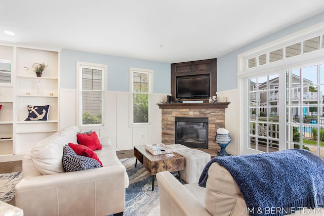 807 Lake St Unit 7, Saugatuck, MI 49453 - living area featuring wood finished floors, a wainscoted wall, a decorative wall, and a stone fireplace