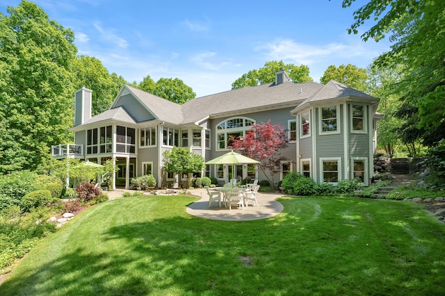 6461 E Bay Ln, Richland, MI 49083 - rear view of house with a chimney, a patio, a lawn, a sunroom, and roof with shingles