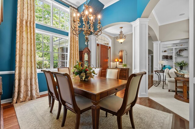 6461 E Bay Ln, Richland, MI 49083 - dining area with arched walkways, crown molding, a chandelier, ornate columns, and wood finished floors