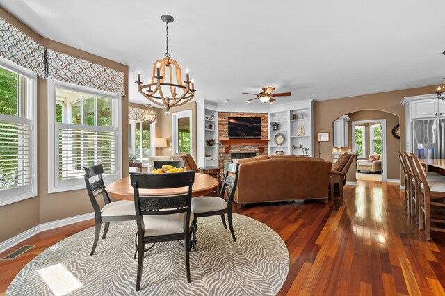 6461 E Bay Ln, Richland, MI 49083 - dining room with arched walkways, a chandelier, dark wood-style floors, a brick fireplace, and baseboards