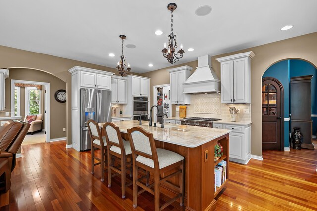 6461 E Bay Ln, Richland, MI 49083 - kitchen featuring custom range hood, stainless steel appliances, arched walkways, light wood finished floors, and recessed lighting
