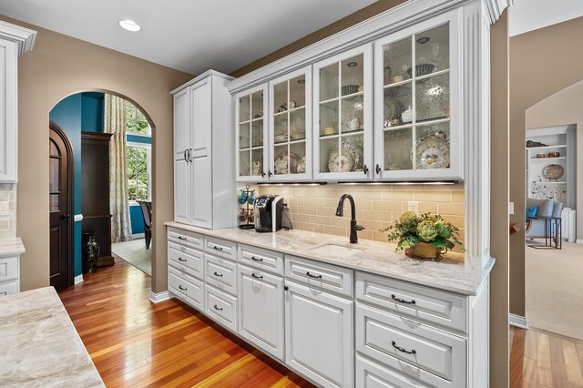 6461 E Bay Ln, Richland, MI 49083 - bar featuring arched walkways, light wood finished floors, decorative backsplash, a sink, and recessed lighting