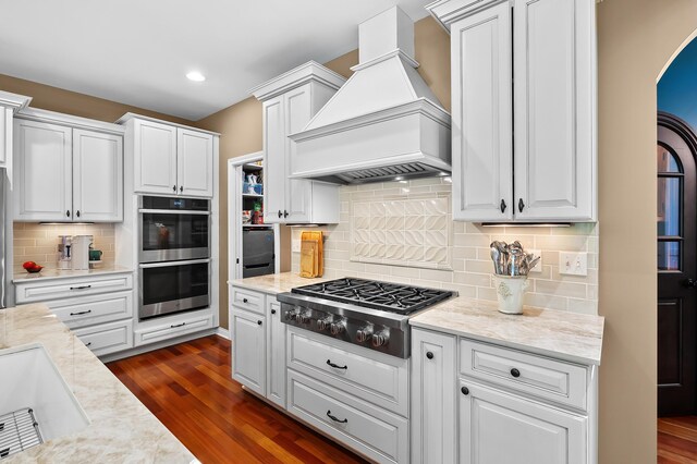6461 E Bay Ln, Richland, MI 49083 - kitchen featuring custom exhaust hood, stainless steel appliances, arched walkways, dark wood finished floors, and recessed lighting