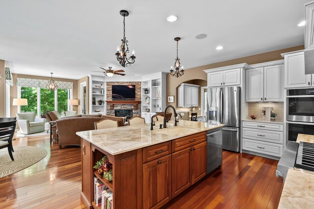 6461 E Bay Ln, Richland, MI 49083 - kitchen with stainless steel appliances, a chandelier, a fireplace, dark wood-style flooring, and white cabinets