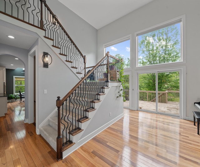 6201 Donovanridge, Dexter, MI 48130 - stairway with a towering ceiling, arched walkways, hardwood / wood-style floors, and baseboards