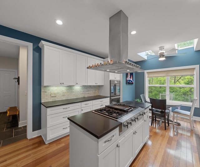 6201 Donovanridge, Dexter, MI 48130 - kitchen with a skylight, stainless steel gas cooktop, island range hood, dark countertops, and baseboards