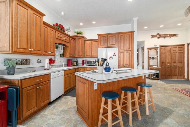 47 Arthur St, Manistee, MI 49660 - kitchen featuring white appliances, a sink, brown cabinets, a kitchen breakfast bar, and crown molding